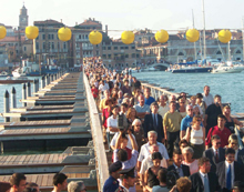 Le persone che percorrono il ponte votivo